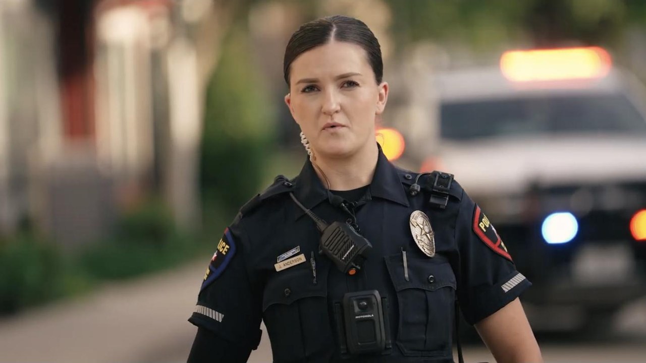 Plano police officer photographed on shift for the department's recruitment film, patrol vehicle light bar out of focus behind her