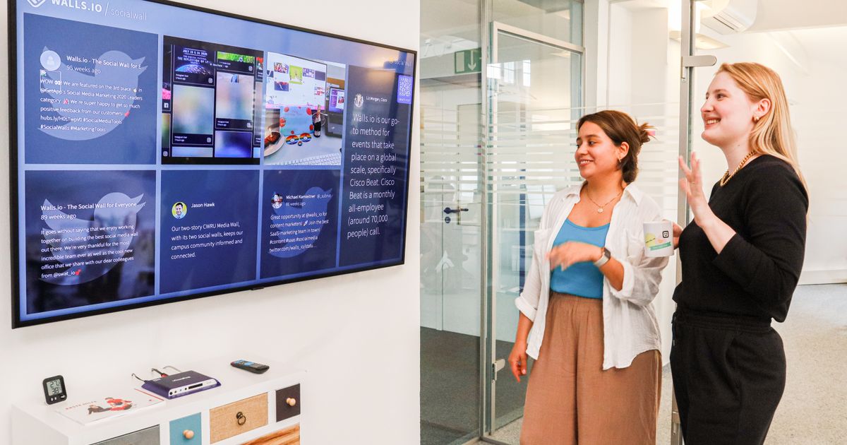 Two colleagues reviewing content on a large digital display during a Dallas digital signage video production planning session